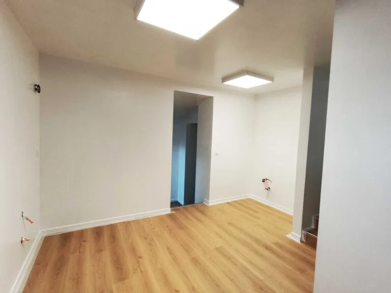 Pièce rénovée avec un sol en parquet clair et des murs blancs, aménagement intérieur à Quimper.